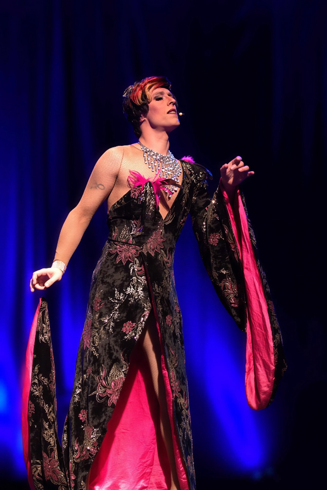 Miss Caline en robe noire et rose sur scène, spectacle cabaret transformiste