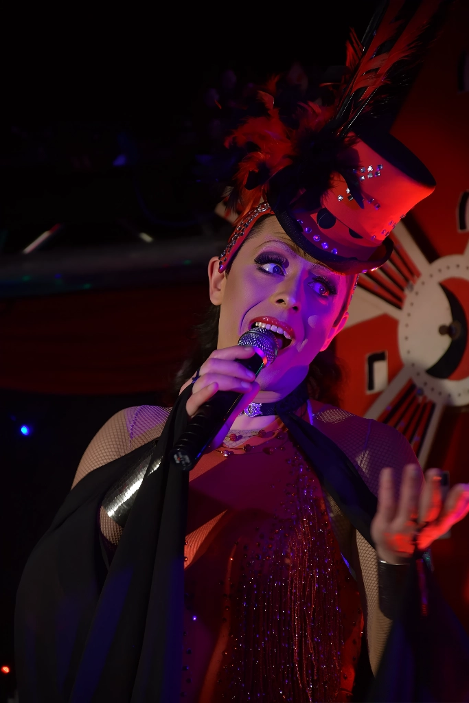 Miss Caline avec chapeau rouge et plumes sur scène cabaret